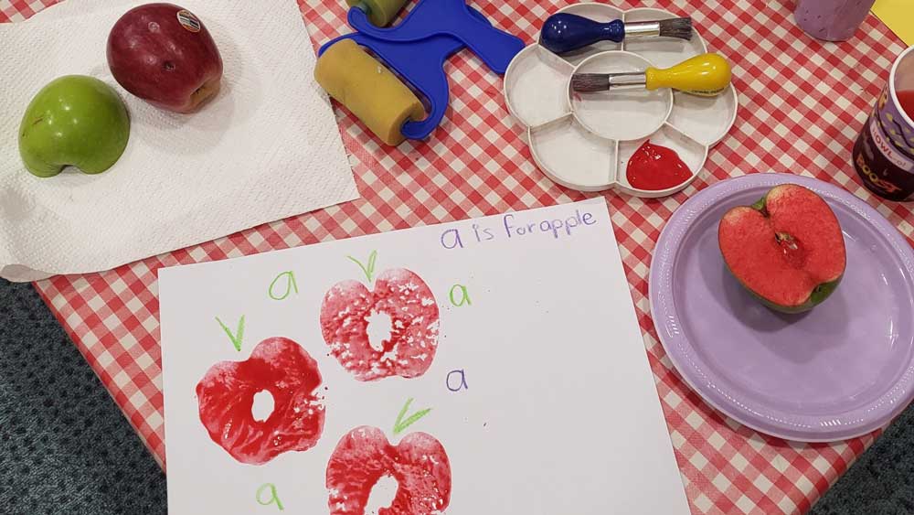 Child’s apple print art and real apples